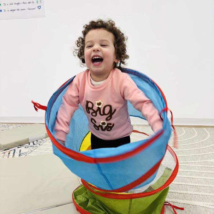 A toddler laughing inside a pop-up play tunnel.