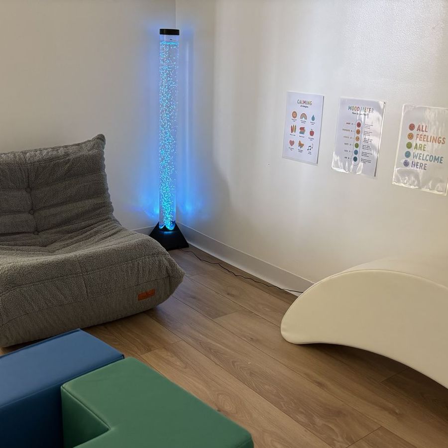 The mindfulness room: a glowing blue bubble tube beside a grey bean-bag lounger and a white wave rocker.