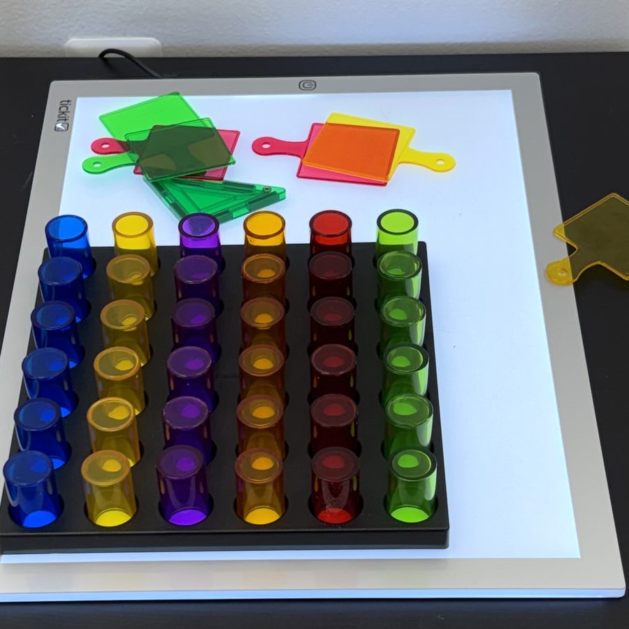 Close-up of the STEM room light table: glowing rows of colorful translucent pegs and color paddles.